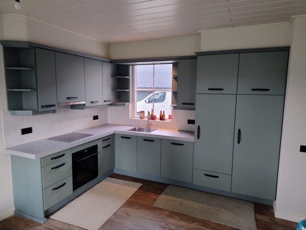 Moderne landelijke keukenrenovatie in Terwolde met groene keukenkastjes, terrazzo blad en zwarte grepen