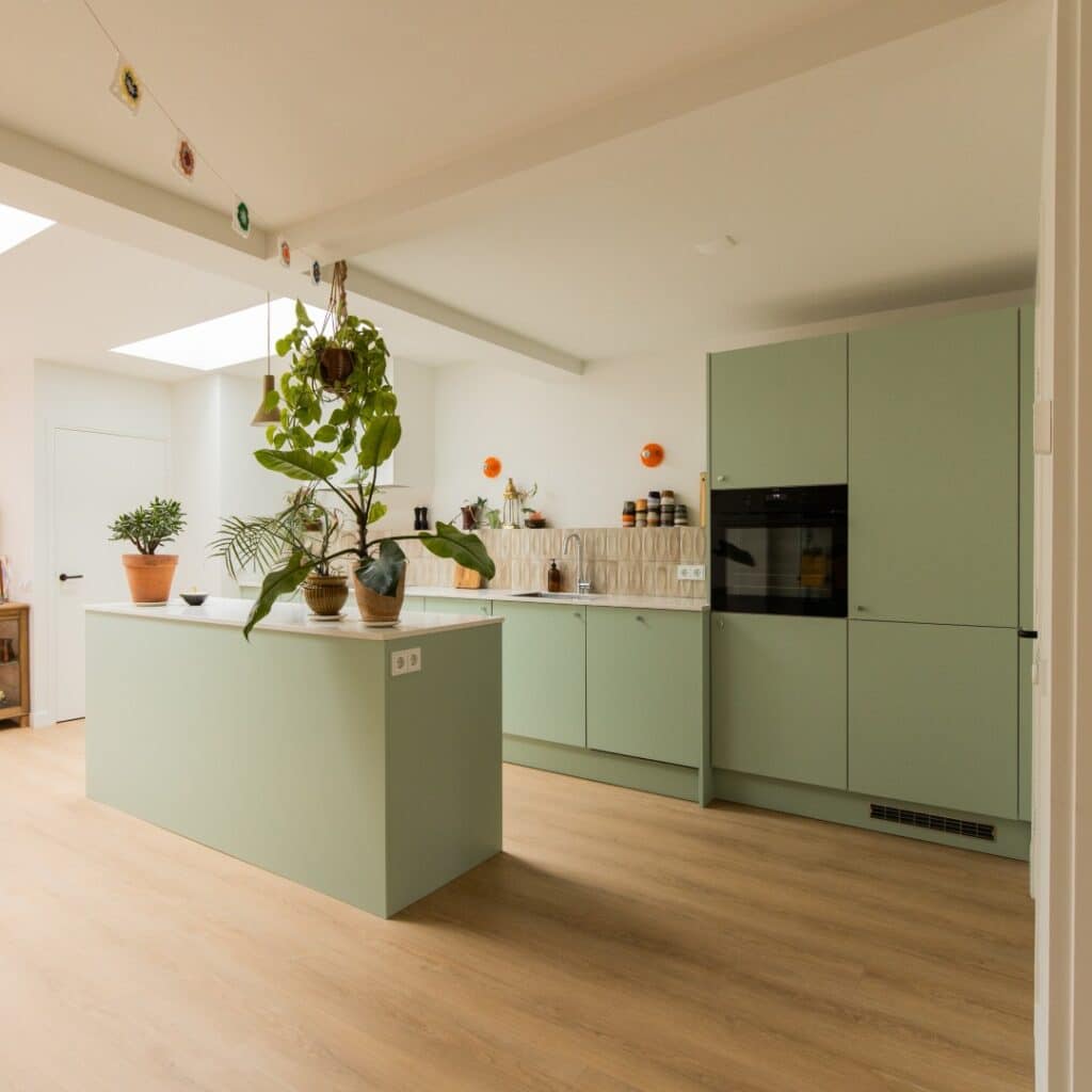 Groene keuken met kookeiland, composiet werkblad en hoge kastenwand, opgeleverd in Twello door STEL Keukens.